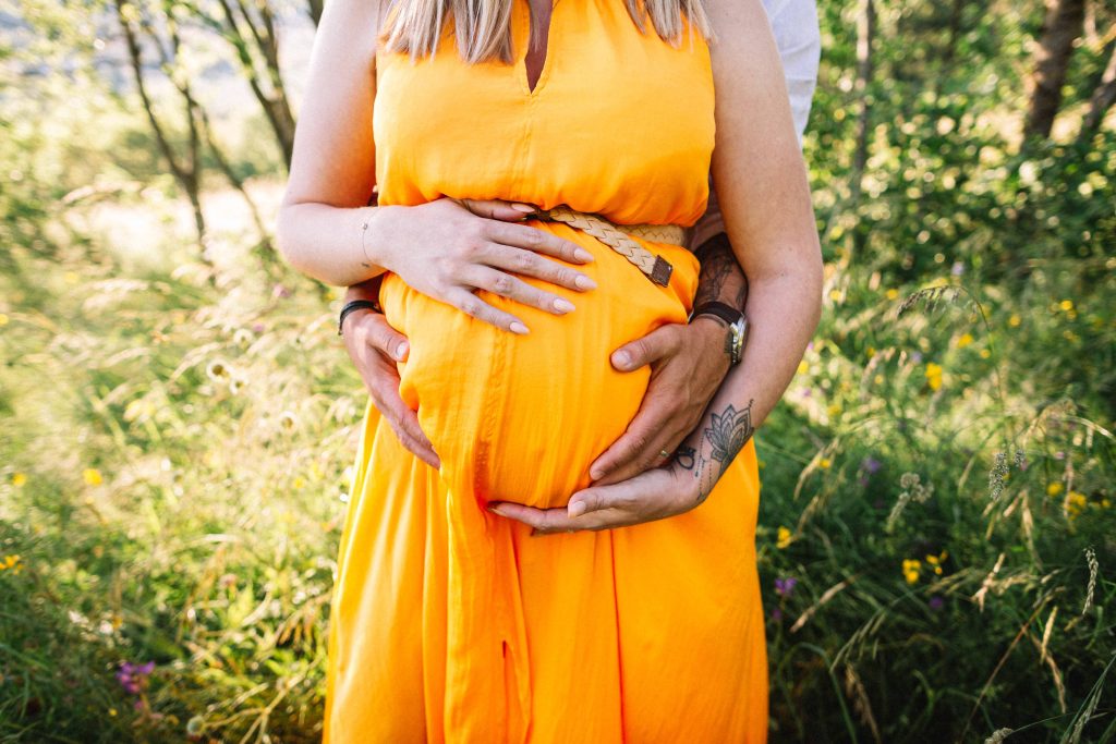gros plan sur le ventre d'une femme enceinte entourés des mains du futur papa