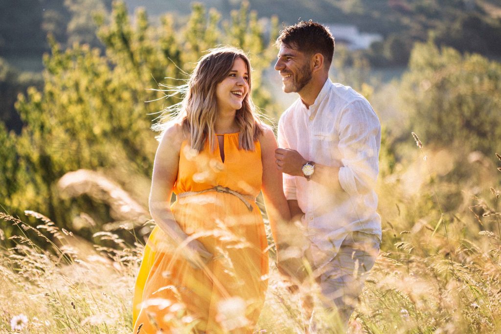 Couple de futurs parents heureux, riant dans les champs